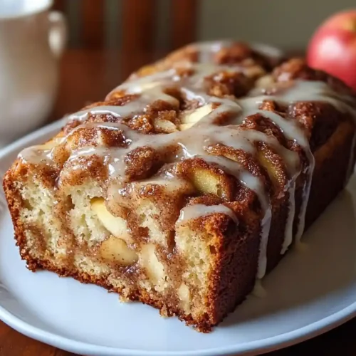 Freshly baked cinnamon swirl apple fritter bread with a golden crust and visible swirls of cinnamon.